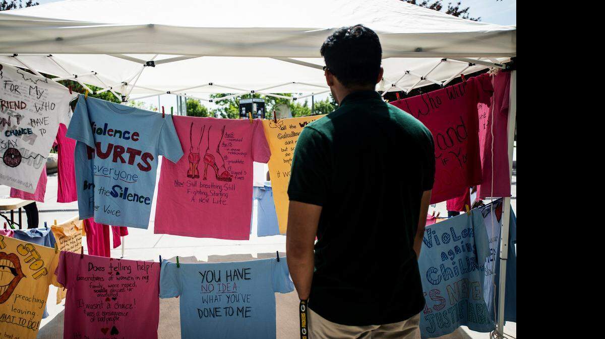 Sanketh Salveru, 18, reads messages about sexual assault during Sexual Assault Awareness Month at UC Merced on Tuesday. The Clothesline Project features shirts with messages by students about sexual violence.