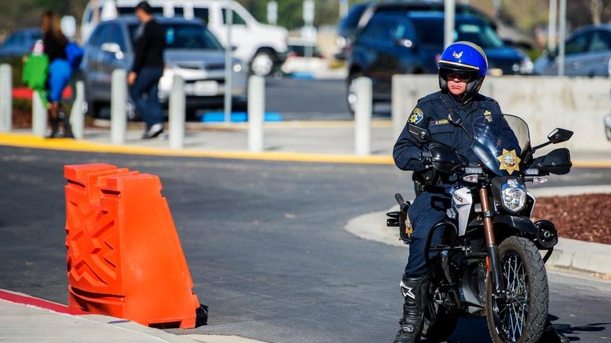 University of California, Santa Cruz police officer Brian Hughes, looks on from his motorcycle as students walk the UC Merced campus in Merced, Calif., on Nov. 6. Classes resumed that day following an on-campus stabbing which left four people wounded before campus police shot and killed the suspect, 18-year-old Faisal Mohammad, of Santa Clara, on the UC Merced campus Wednesday morning.