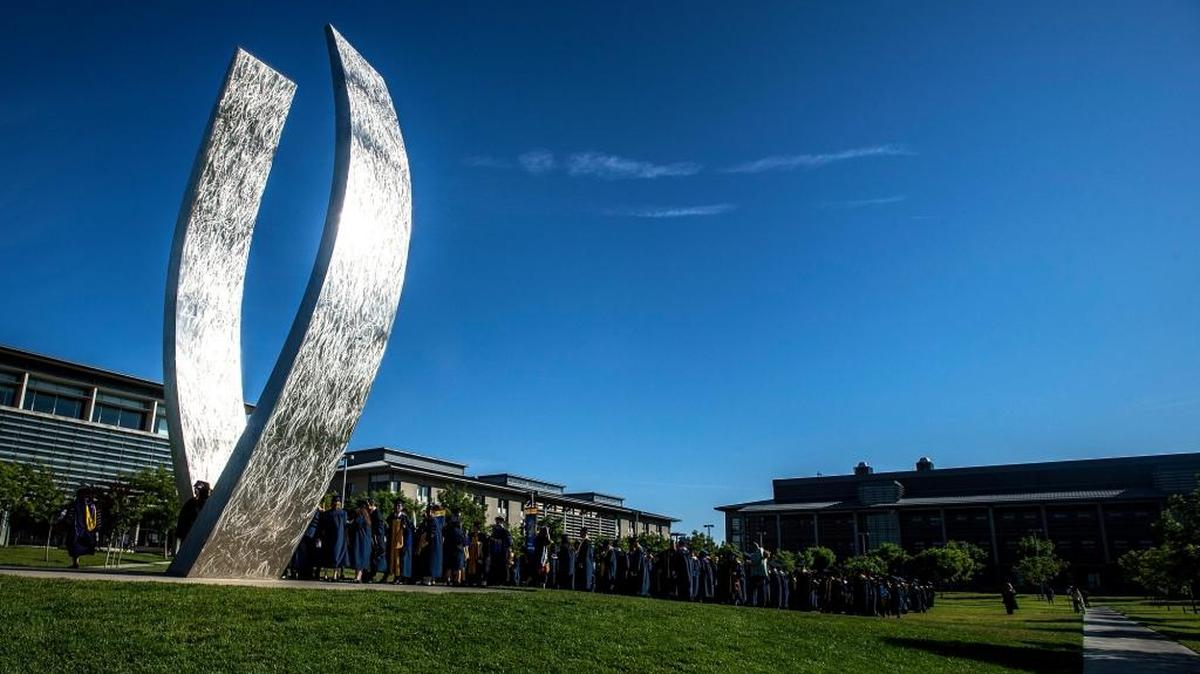 UC Merced graduates gather at the campus sculpture titled “Beginnings” prior to the commencement ceremony for the School of Engineering and the School of Natural Sciences last year.