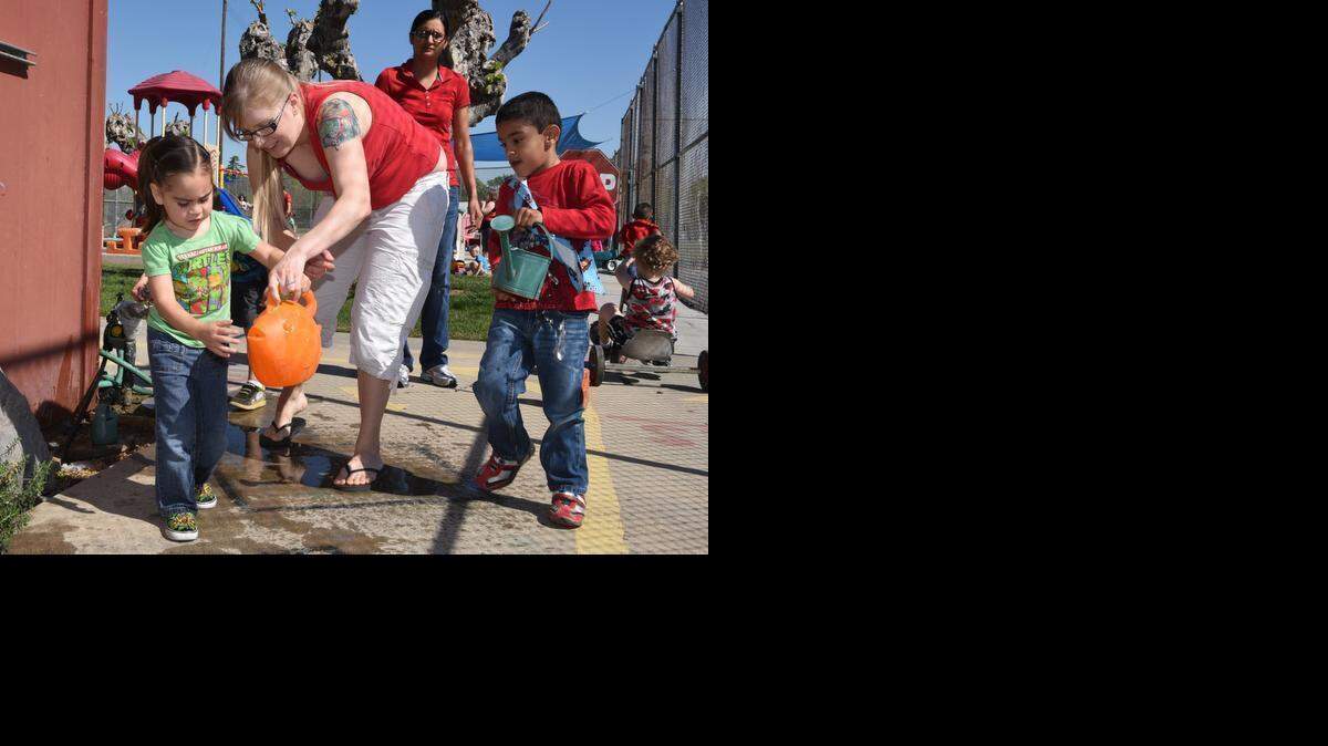 
Parent Beth Nickerson helps Zay Lopez, 3, with a water container as Bikrum Bagri, 5, watches with his watering can in hand Friday at Merced Parent Preschool. Parents are required to volunteer in the classroom one day a week.
