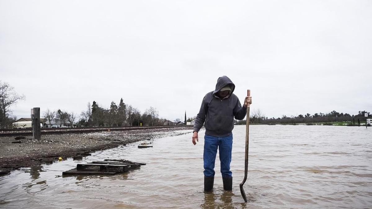 Hilarion Marquez, 50, of Le Grand, works to keep the end of a pump clear while pumping water from a flooded section of land next to the railroad tracks across from Live Oak Farms on East Jefferson Street in Le Grand, Calif., on Saturday, Feb. 11, 2017. According to authorities, flooding along Mariposa Creek forced some residents to evacuate their homes Saturday. About 25 homes were evacuated, according to a statement from the Merced County Office of Emergency Services.