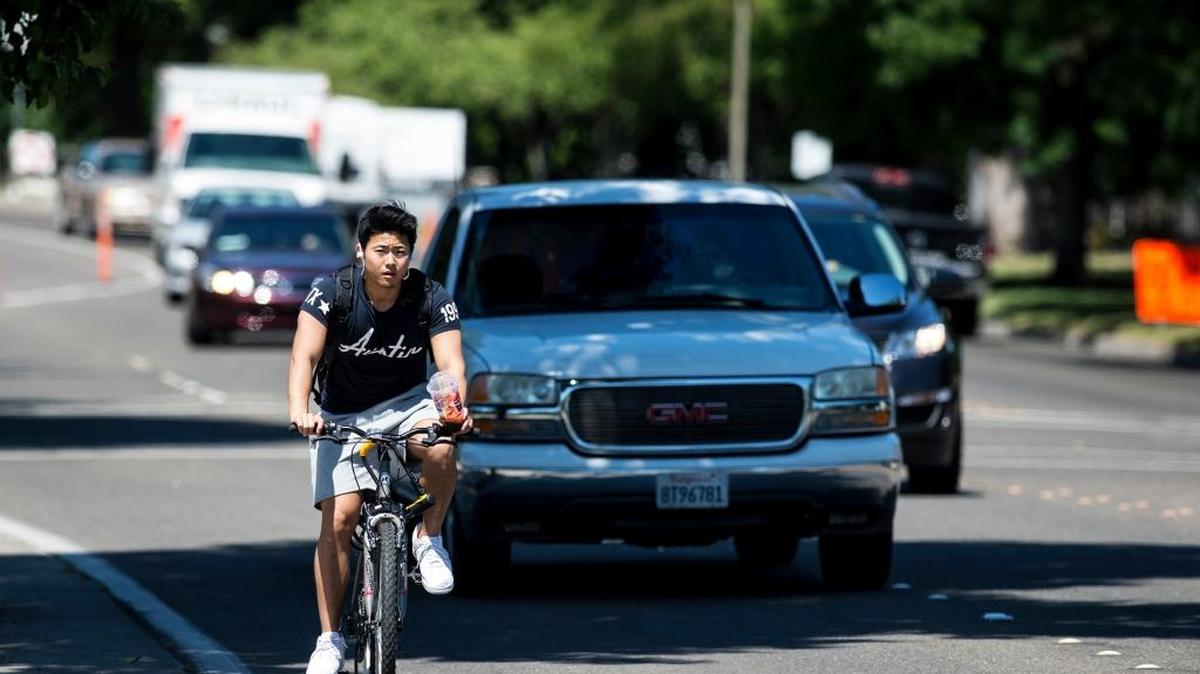 A man rides a bike with a beverage along M Street past Applegate Park in Merced Calif., on Thursday, May 4, 2017. According to The National Weather Service in Hanford, record highs were already broken by midday in areas around the central San Joaquin Valley.