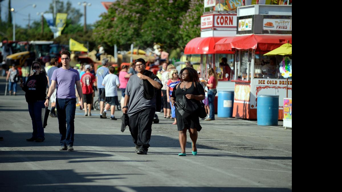 
Dozens of people walk between food booths during the early hours of the first day of the Merced County Fair on Wednesday. The National Weather Service in Hanford is predicting an unseasonably warm weekend.
