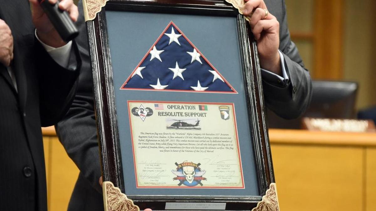 Mayor Stan Thurston talks about an American flag, held by City Manager Steve Carrigan, on Monday flown in Afghanistan that was presented to the city of Merced by Army 1st Lt. Kyndall M. Burgfeld.