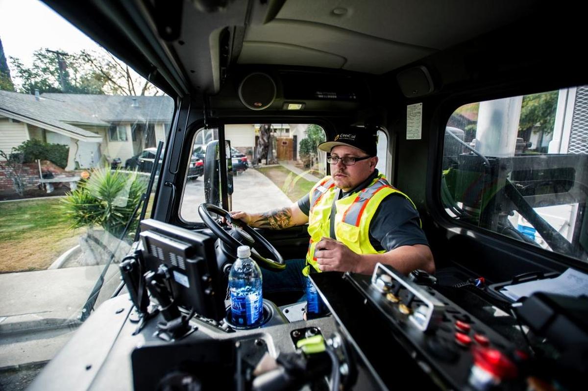 Mike Schlessinger, 33, of Merced looks in the side mirror while collecting green waste in Merced on Tuesday, Dec. 8, 2015.