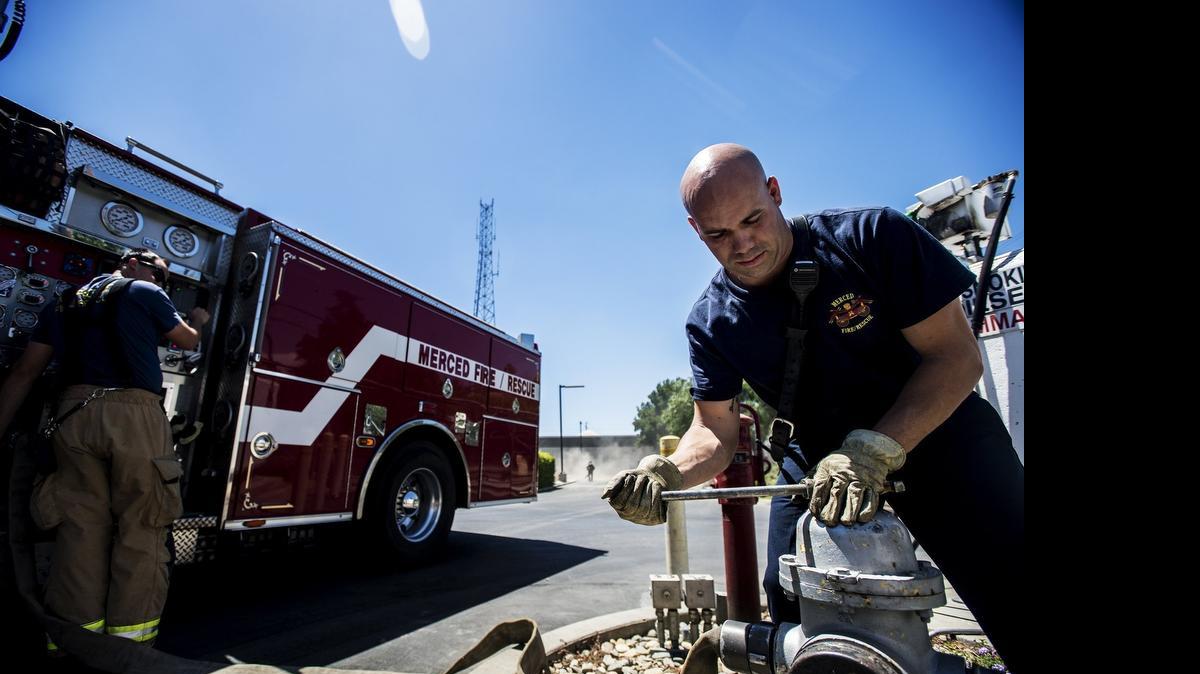 
Merced Fire Department rookie firefighter Joe Jarratt, right, assists engineer Nate Frankhauser, left, in filling the truck’s water tank Tuesday in Merced. The city of Merced adopted a new budget this week, which increases funding to public safety.
