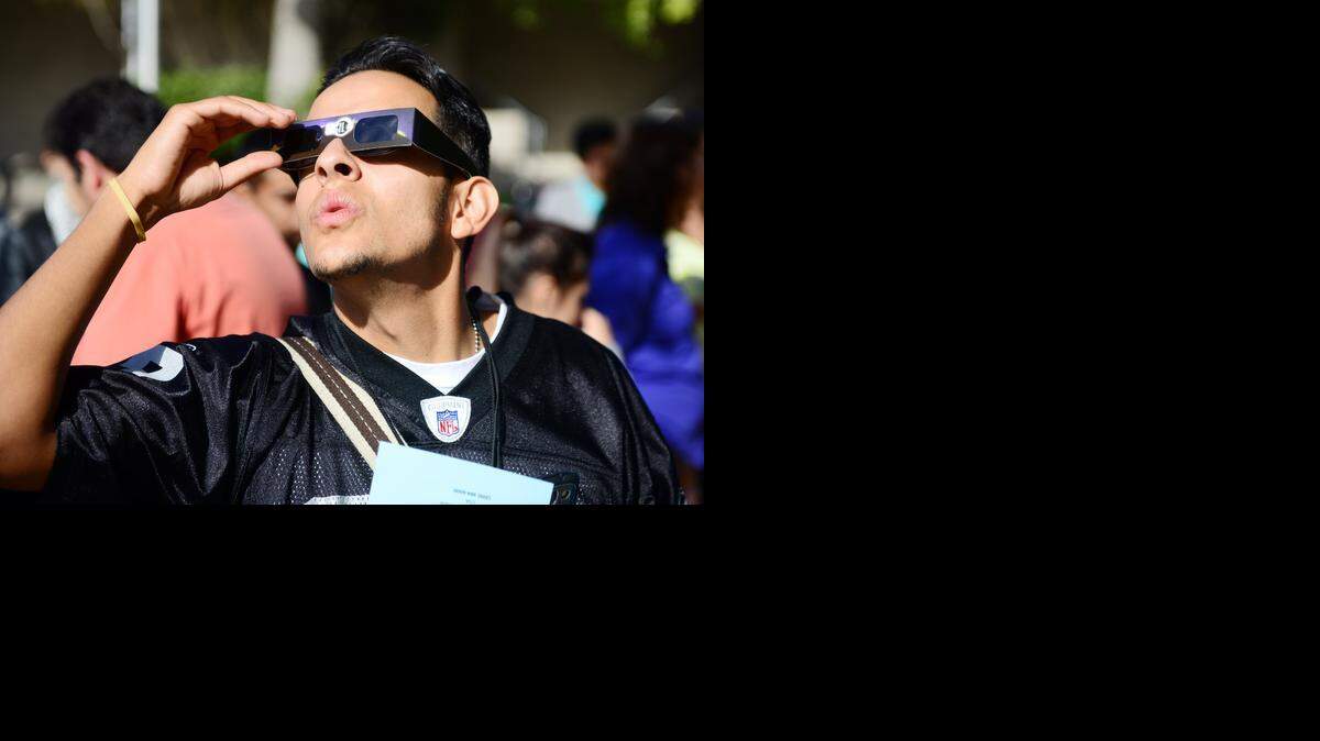 
Albert Godinez, 23, of Turlock, a member of the Journalism Club, checks out the solar eclipse using special glasses on Thursday at Merced College. Dozens of students turned out to get a safe look at the eclipse.
