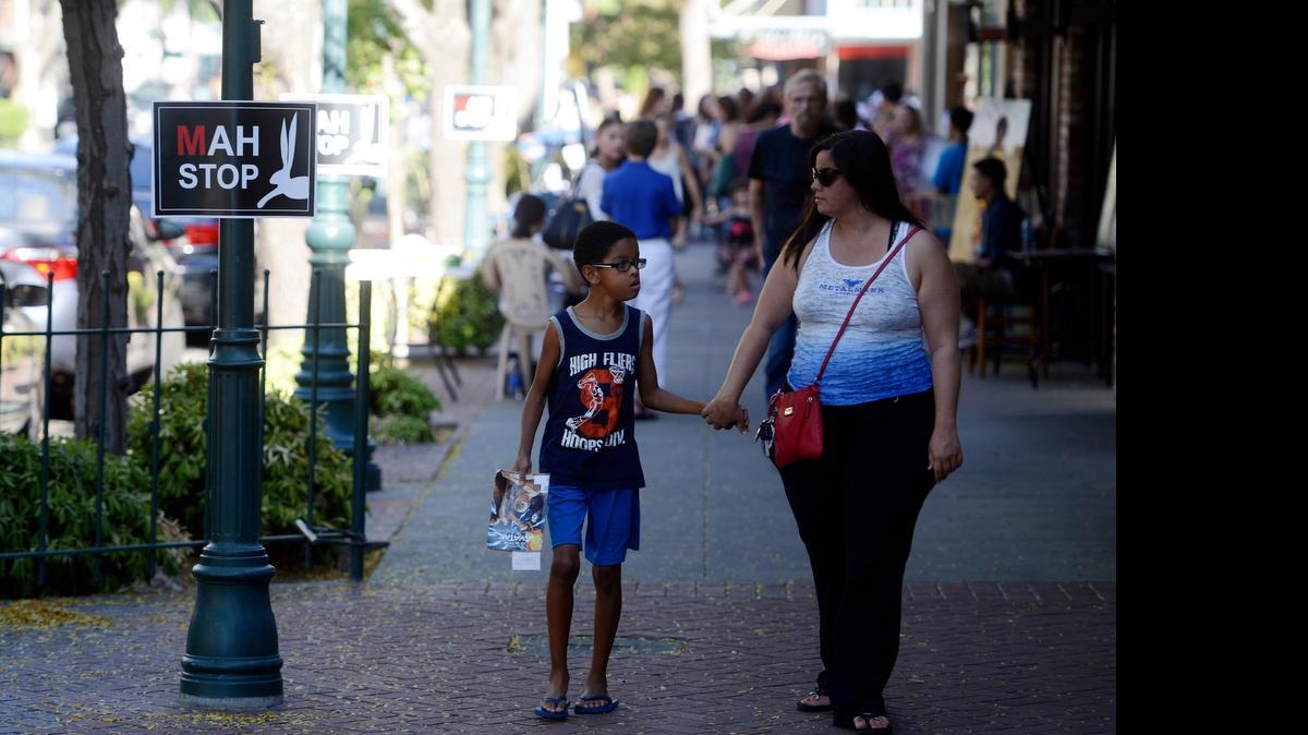 
Families walk Main Street during the Merced Art Hop on Saturday. A few thousand people typically attend the quarterly event that celebrates expression through music, painting, performance and other arts.
