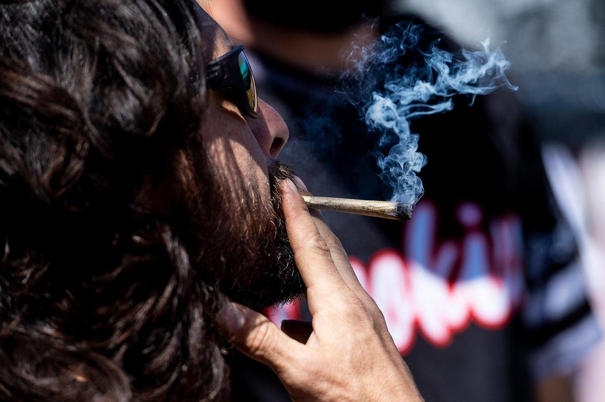Joe Scotia, 42, of Fresno, smokes a joint during a 420 celebration on Third Avenue in Gustine, Calif., on Wednesday, April 20, 2022. The event included smoke shop items for sale, food vendors and live music.
