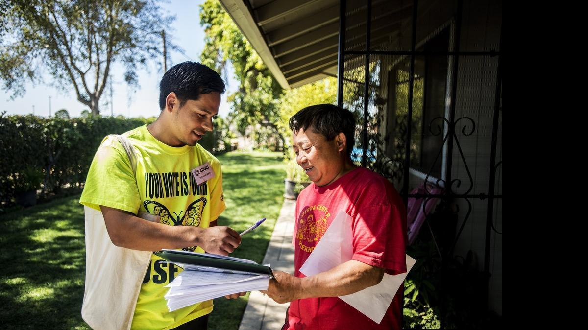 
Communities for a New California volunteer and recent UC Merced graduate Hector Ramirez, left, speaks with Merced resident Xiachoua Vang while canvassing door to door in south Merced on Saturday. The organization has set out to encourage residents to attend an upcoming Independent Districting Advisory Committee meeting. Currently, all six City Council members live north of Bear Creek Drive.
