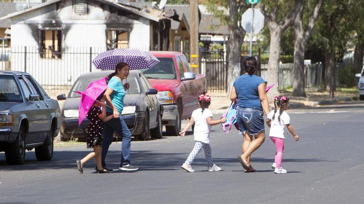 
Merced residents use umbrellas to shade themselves from the sun on a walk in Merced on Wednesday. 
