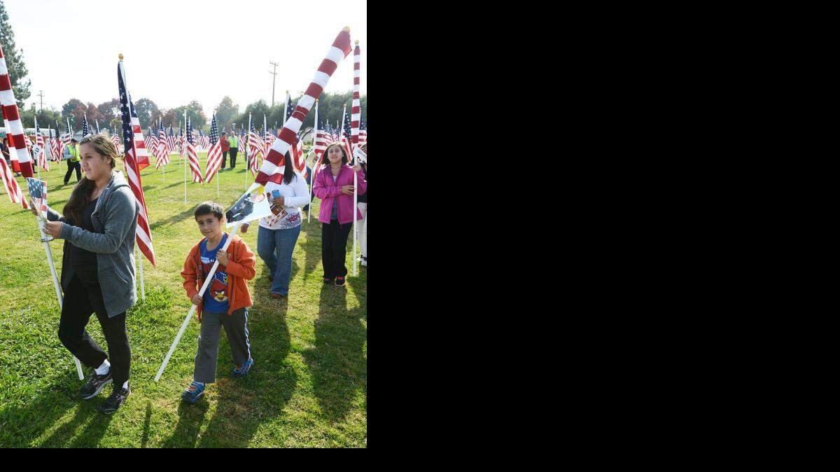 
Julia Tovar, 14, at left, and Alex Tovar, 7, both of Atwater, remove flags that were placed to honor their dad and other family members in the armed services during the Field of Honor closing ceremony at Merced College on Veterans Day last year.
