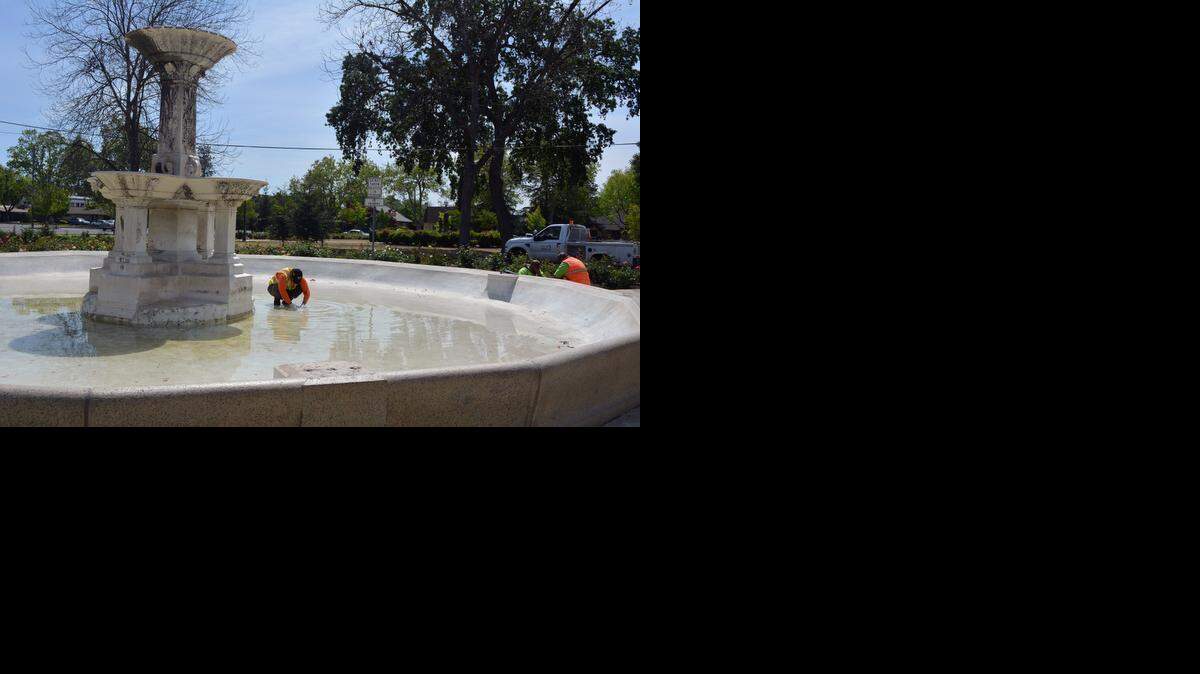 
City of Merced employee Armando Garibau clears debris from the drain at Laura’s Fountain in Applegate Park on Monday. 
