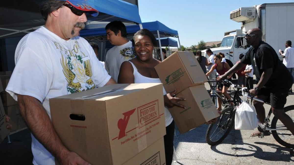 
An example of Marci Stenberg’s work: Volunteers help families with boxes of groceries and household items during a Feed the Children giveaway at the Merced County Food Bank in 2011.