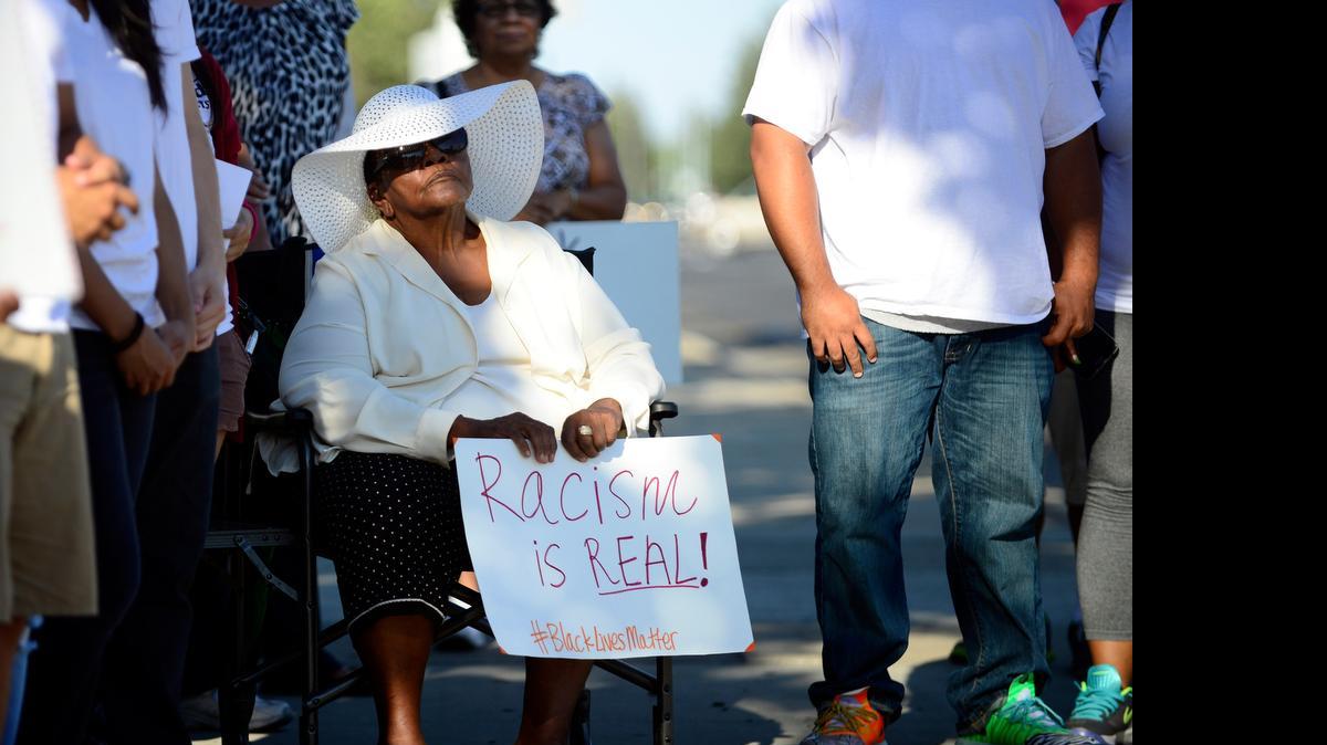 
Barbara Roland, 71, of Merced holds a sign while surrounded by demonstrators in Merced on Wednesday at Olive Avenue and R Street. About 50 people came together to show solidarity with the nine people killed last week in a historically black church in South Carolina by a white supremacist.
