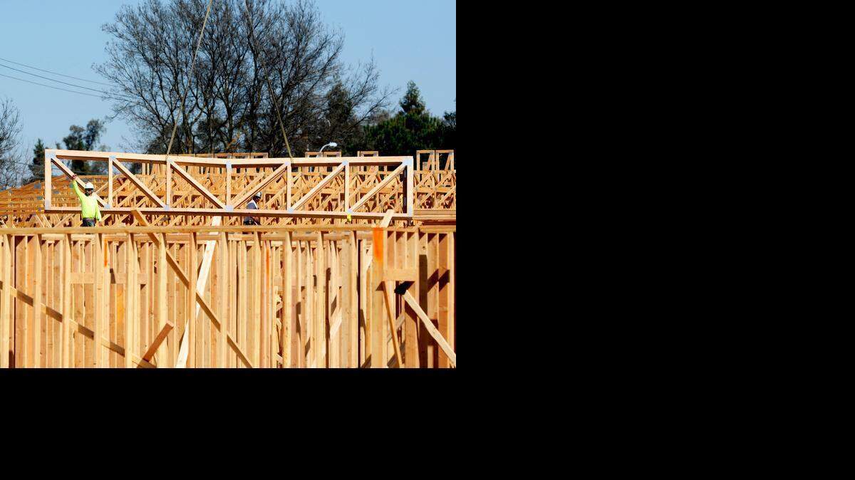 
Construction workers guide a piece of framework into place at a construction site on the corner of R Street and Yosemite Avenue on Friday in Merced.
