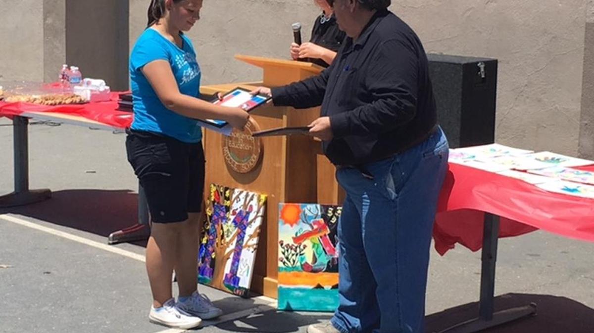 A Hoover Middle School student receives a certificate Thursday, May 26, 2016, for her work on a new mural inspired by the school’s Husky Pack, which teaches students to be prepared, accountable, compassionate and knowledgeable.