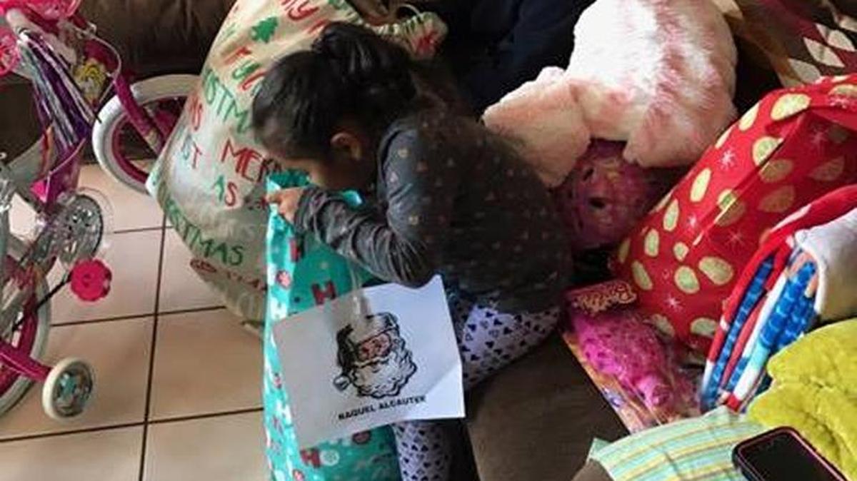 Two children open the gifts they received through Operation Holiday Toy Drive.