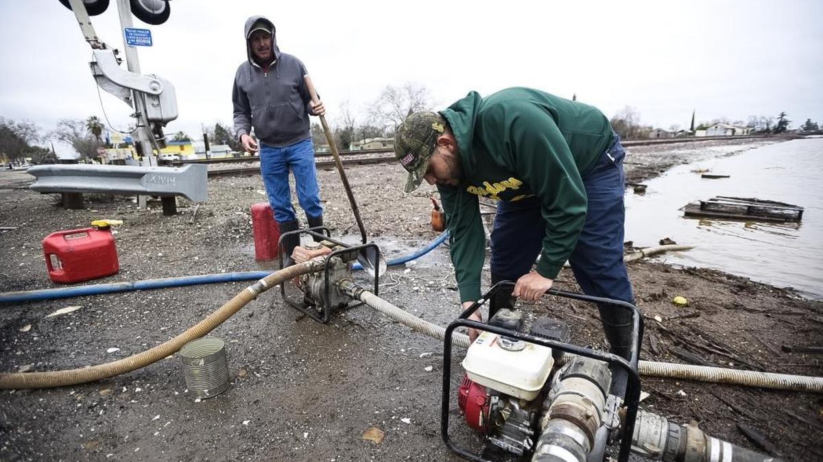 Leo Marquez, 22, of Le Grand, right, and his uncle Hilarion Marquez, 50, of Le Grand work to start pumps to remove water from a flooded section of land along the railroad tracks across from Live Oak Farms on East Jefferson Street in Le Grand on Saturday.