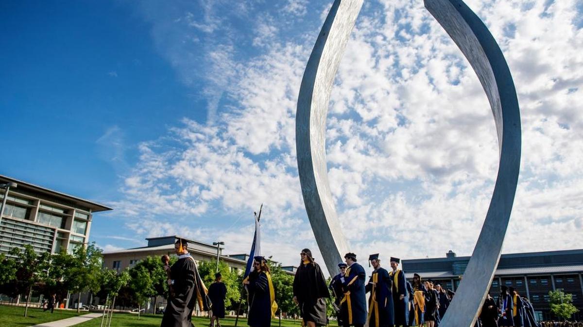 UC Merced graduates walk through the campus sculpture titled “Beginnings” during commencement for the school of Social Sciences, Humanities and Arts at UC Merced in Merced, Calif., on Saturday, May 14, 2016.