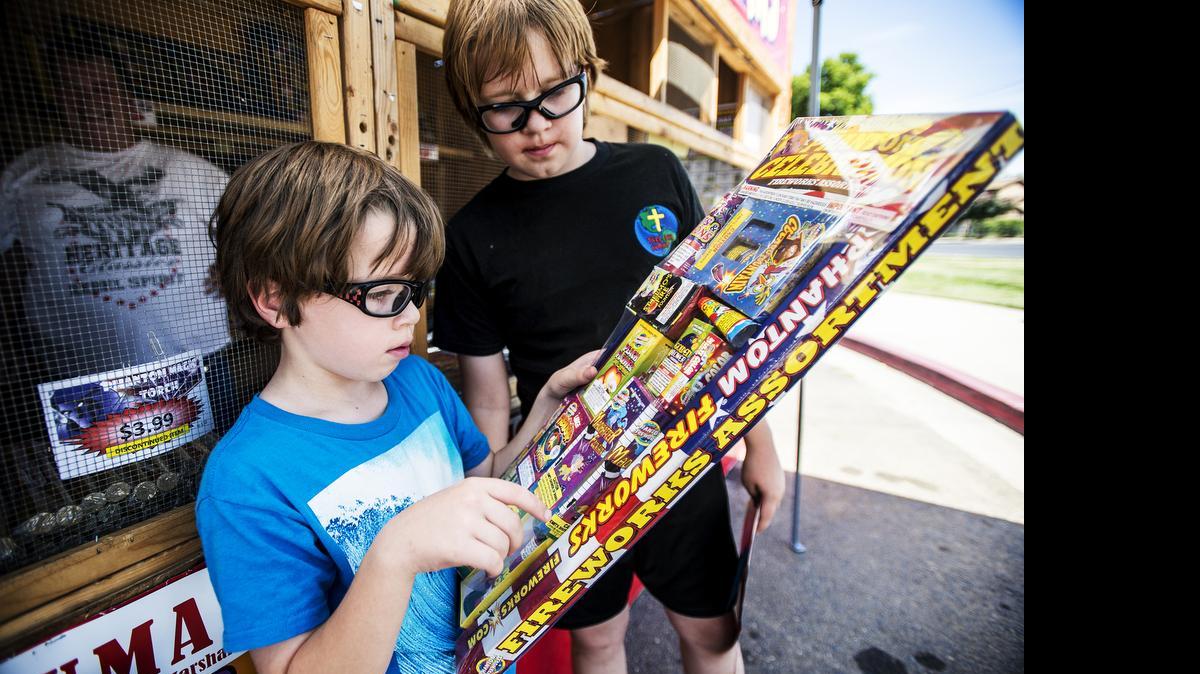 
Devin Cherf, 6, left, and brother Dylan, 10, right, look over the package of fireworks purchased with their family from the Phantom fireworks stand at Parsons and East Childs avenues in Merced on Tuesday.
