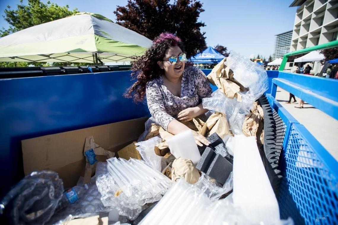 University of California, Merced freshman Ilsia Gonzalez, 18, of Los Angeles, participates in a dumpster diving game as she attempts to find a ticket that would win her a free shirt, during Earth Day on the campus of UC Merced in Merced, Calif., on Thursday, April 20, 2017.