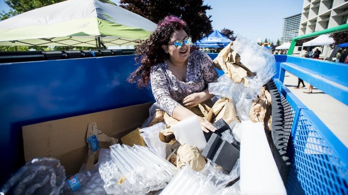 University of California, Merced freshman Ilsia Gonzalez, 18, of Los Angeles, participates in a dumpster diving game as she attempts to find a ticket that would win her a free shirt, during Earth Day on the campus of UC Merced in Merced, Calif., on Thursday, April 20, 2017.