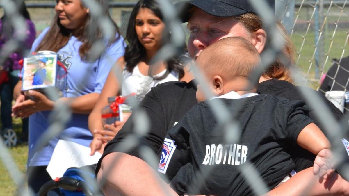 Noah Sisk’s grandmother Cynthia Hooker holds his brother Nehemiah, who was injured in the Thursday afternoon crash that killed Noah and his mother, during a Los Banos Little League ceremony on Saturday, April 16, 2016, to remember the 5-year-old T-ball player.