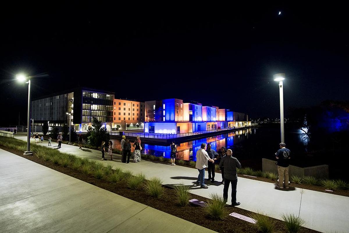 New student housing facilities Granite Pass, center, and Glacier Point, left, are seen next to Little Lake during a building lighting ceremony to celebrate the opening of the first three buildings of the Merced 2020 Project, on the UC Merced campus in Merced, Calif., on Thursday, Aug. 16, 2018.
