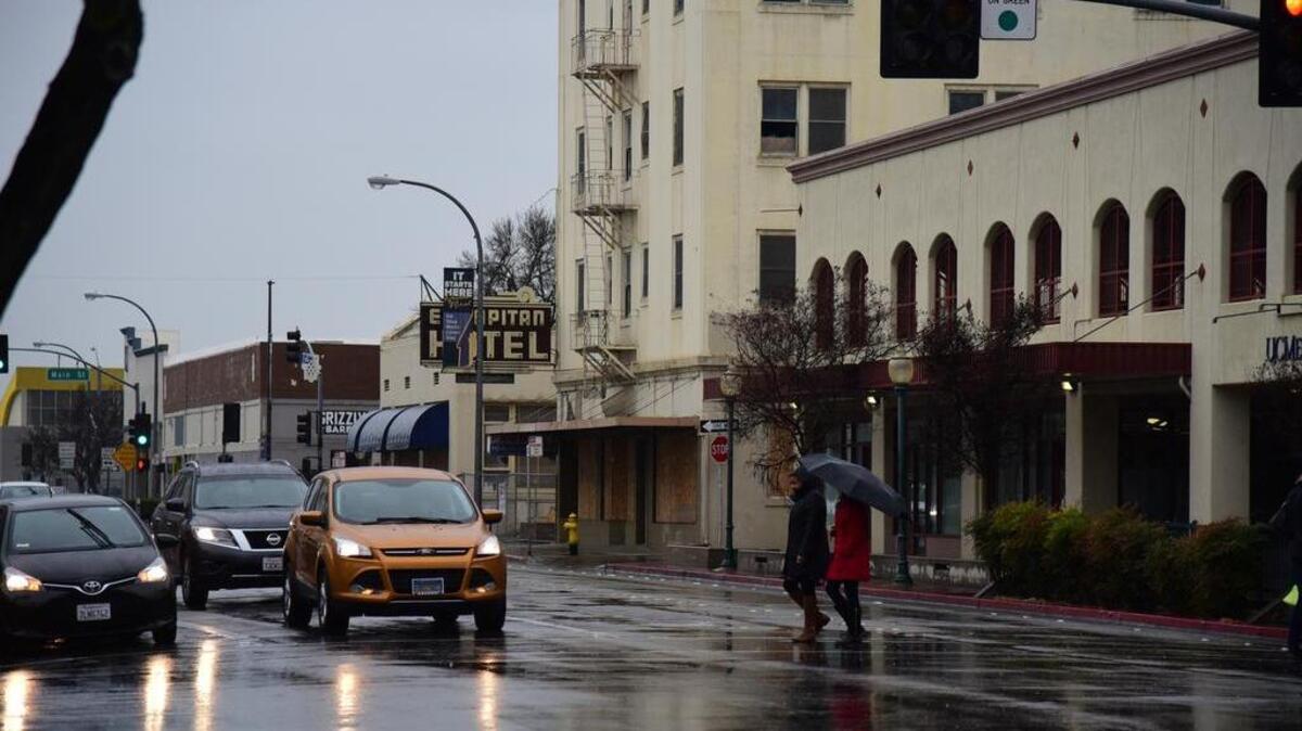 Pedestrians walk in the rain across 18th Street in Merced on Monday Feb. 26, 2018.