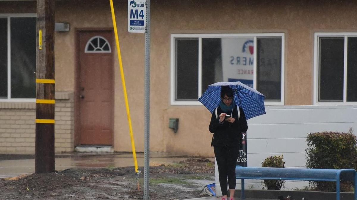 A woman waits for The Bus on G Street near Alexander Avenue in Merced on a rainy Thursday, March 1, 2018. As of 4 p.m., Merced saw a quarter-inch of rain, According to the National Weather Service in Hanford.