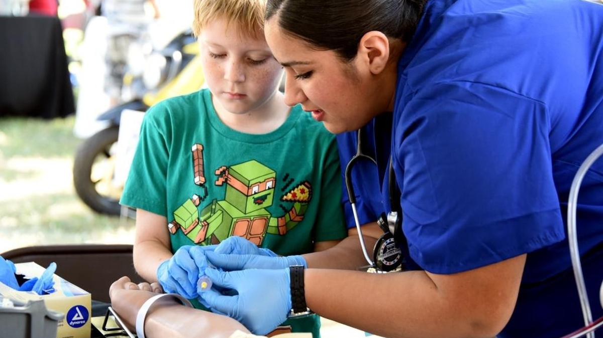 Areli Sarabia with the Merced County Office of Education’s medical assistance program teaches 8-year-old Keegan Reighow to draw blood at a booth during the 2015 Sober Fest in Merced. The second year of the event will take place Saturday, Sept. 10, 2016, at the Merced County Courthouse Park.