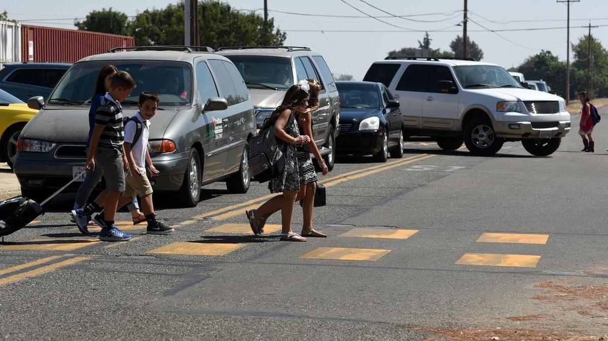 
Children are pictured Monday afternoon in a crosswalk near McSwain School on Scott Road in Merced. An SUV, at right, turns and crosses a double line as another child walks in the middle of the road.


