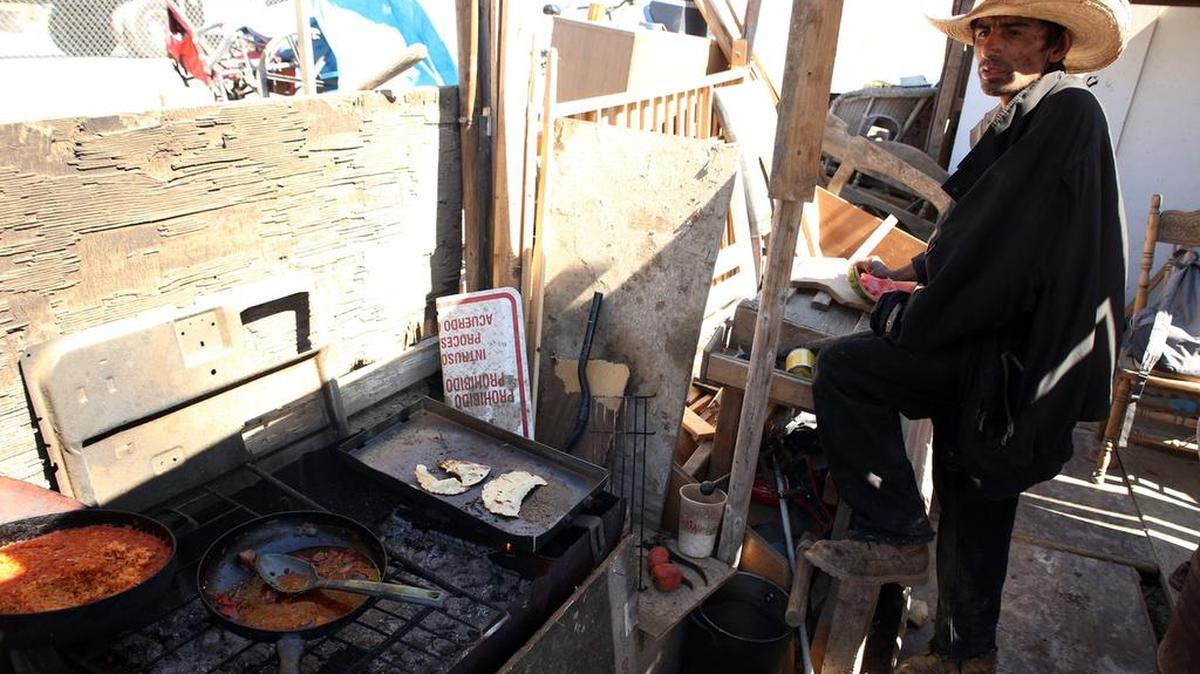 Juan Iglesias readies a meal outside his shack in the homeless encampment between Mendota and Firebaugh in October.