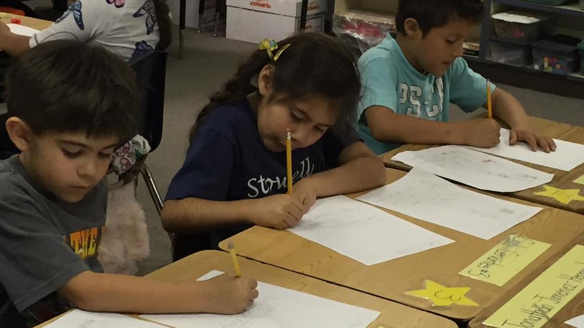 From left, first-graders Isaiah Villanueva, Cindy Cervantes and Haniel Hernandez pen their letters of thanks and appreciation to World War II veteran John Fries.