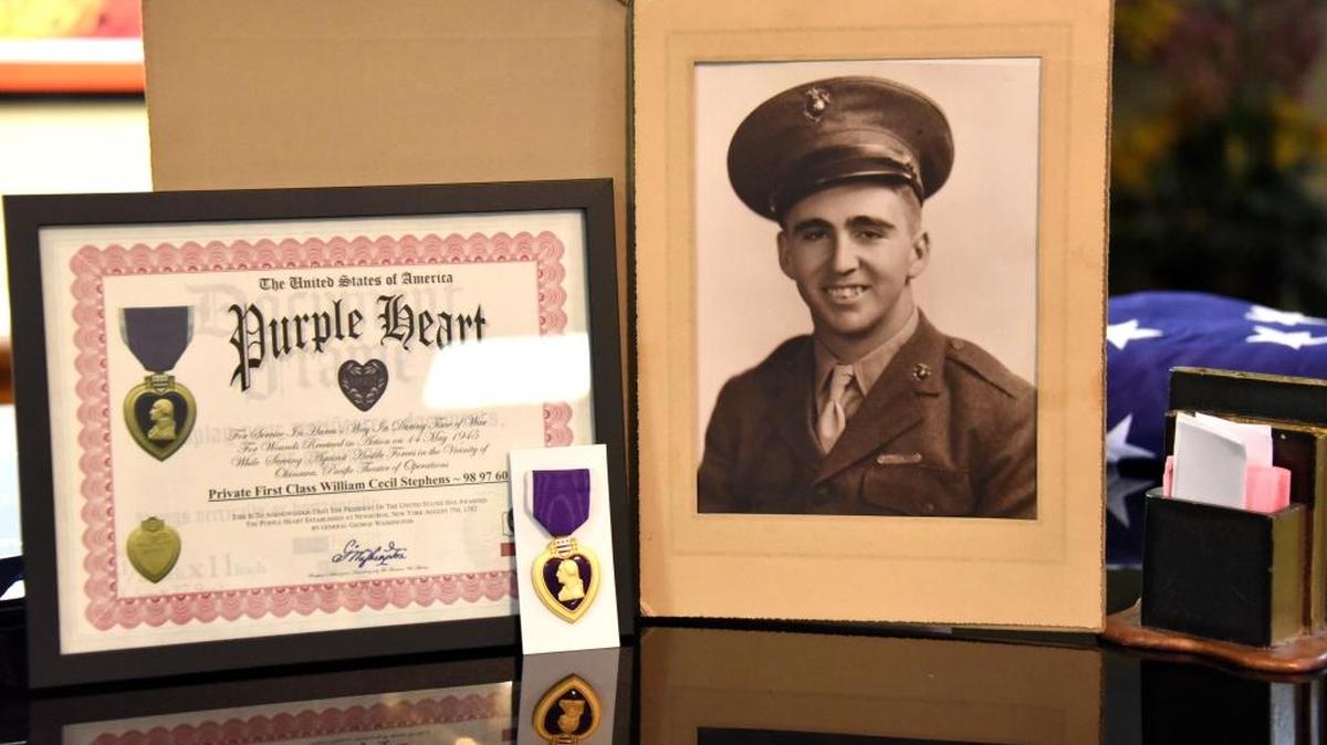 Cecil Stephens is seen in a photo from when he served in the 1st Division Marines in 1944-45 during WWII. Next to the portrait is a certificate of the Purple Heart award he earned for being wounded in the Battle of Okinawa in Japan.