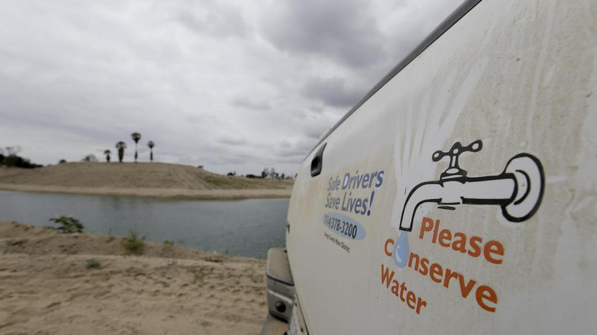 A sign urges water conservation in front of recycled wastewater used to recharge an underground aquifer at a Orange County Water District facility in Anaheim in May 2016.