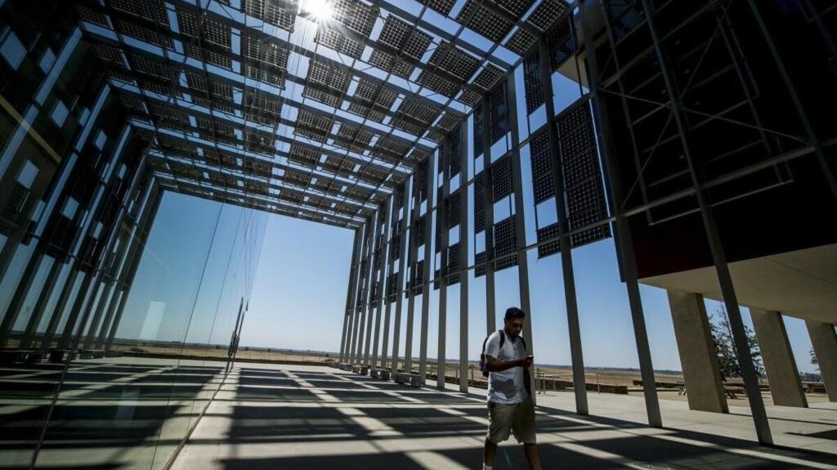 A student walks beneath solar panels that provides both shade and power for UC Merced, the site of a Saturday symposium on parenting and family.
