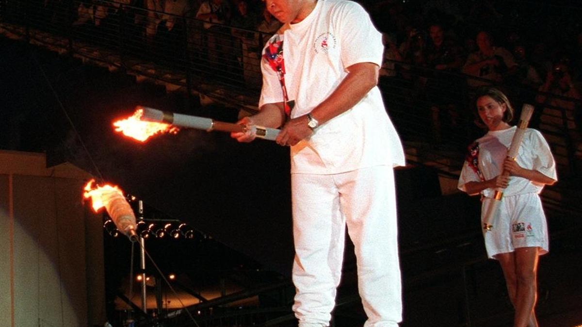 American swimmer Janet Evans looks on as Muhammad Ali lights the Olympic flame during the 1996 Summer Olympic Games opening ceremony in Atlanta. Ali, the magnificent heavyweight champion whose fast fists and irrepressible personality transcended sports and captivated the world, died Friday, June 3, 2016. He was 74.