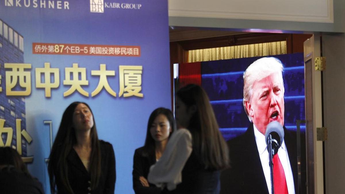 A projector screen shows footage of U.S. President Donald Trump as workers wait for investors at a reception desk during an event promoting EB-5 investment in a Kushner Companies development at a hotel in Shanghai, China, on Sunday. The sister of President Trump's son-in-law, Jared Kushner, has been courting Chinese investors using a much-criticized federal visa program that provides a path toward obtaining green cards.