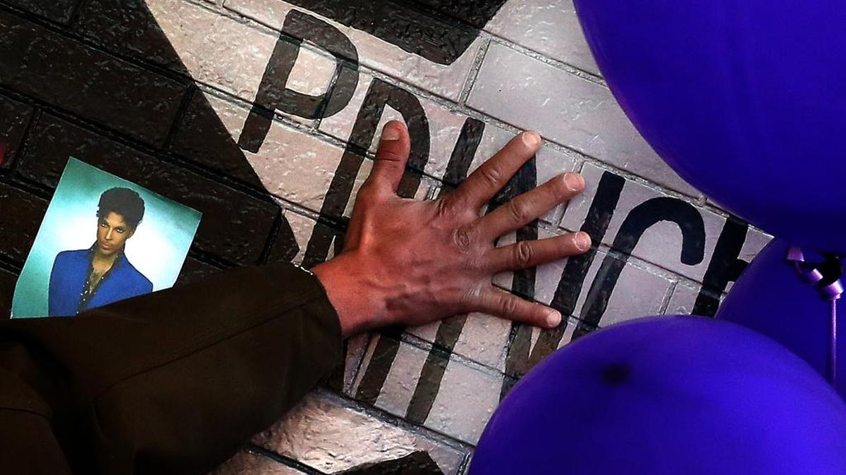 A mourner and fan touches the star for Prince on a wall at First Avenue where the singer often performed in Minneapolis.