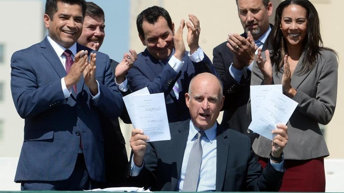 Gov. Jerry Brown holds up four bills he signed related to climate change on Sept. 14, 2016, in downtown Fresno. One of the bills, AB 1613, directs $900 million in “cap-and-trade” auction funds to greenhouse gas reducing programs that benefit disadvantaged communities, support clean transportation and protect natural ecosystems. However, Brown failed to persuade the Legislature to reauthorize the cap-and-trade program of limiting carbon emissions.