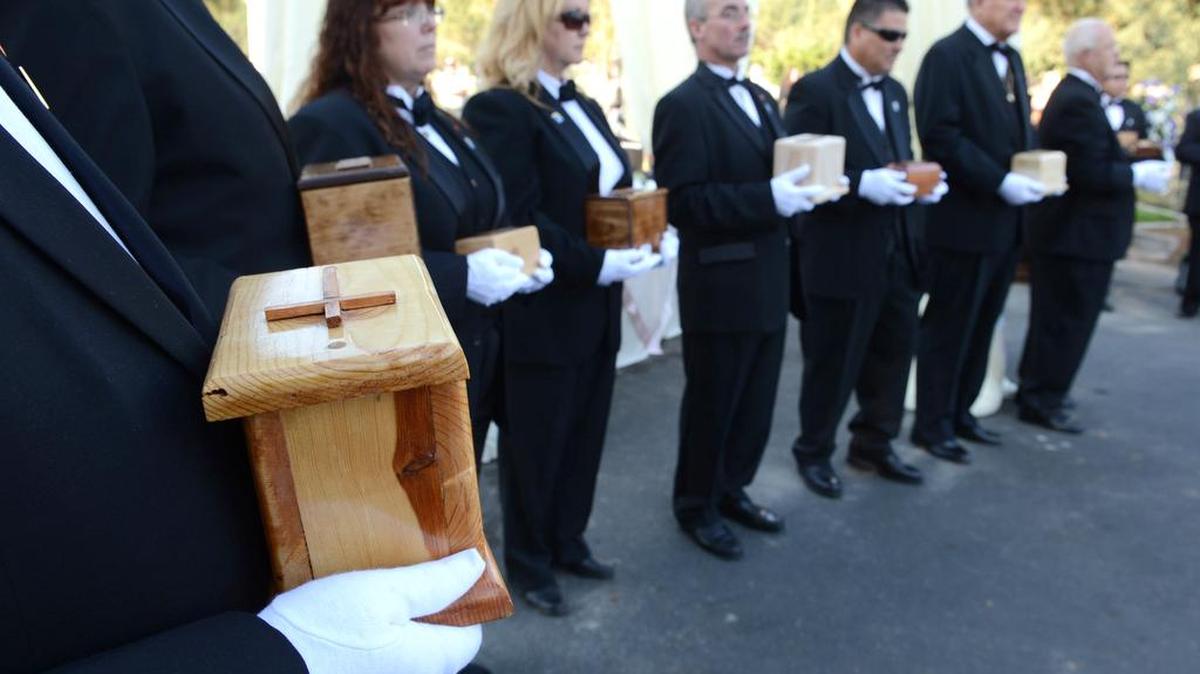 Volunteers hold small wooden urns containing remains at the Garden of Innocence during a memorial service and burial of 23 children in Fresno County. A new Garden is being created in Merced.