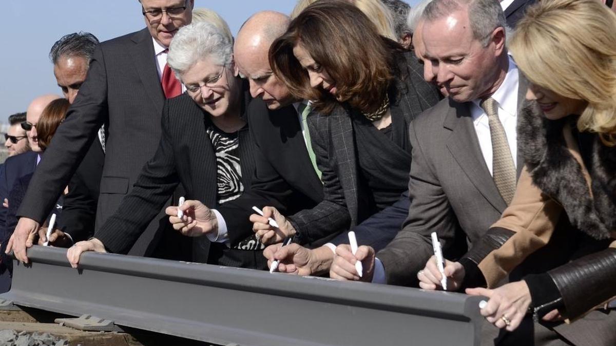 Gov. Jerry Brown, center, ceremoniously signs a section of rail, flanked by his wife, Anne Gust Brown, center right, and Gina McCarthy, administrator of the federal Environmental Protection Agency, and other dignitaries at the symbolic groundbreaking for the bullet train project in downtown Fresno on Jan. 6, 2015.