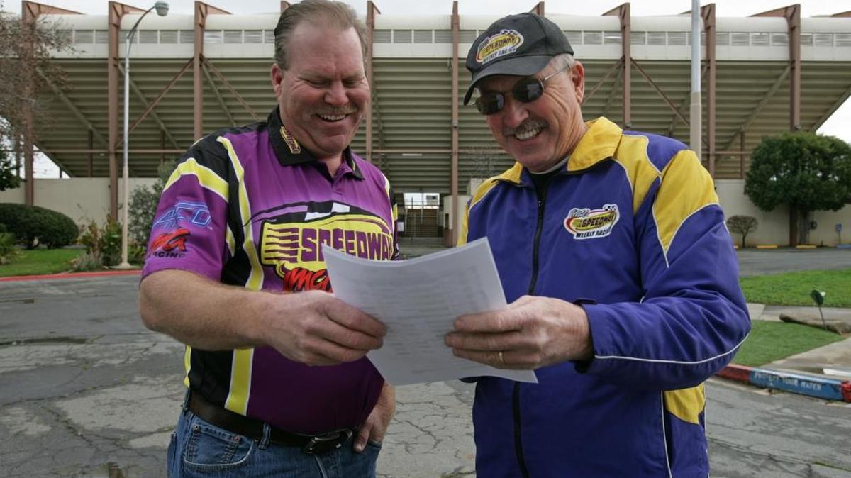 Ed Parker, left, new owner of Merced Speedway, goes over the 2016 season schedule with Doug Williams, newly appointed race director. Both men have deep roots in the Merced racing community. They hope to fill the historic speedway’s grandstand, background, with community- and family-themed programs.