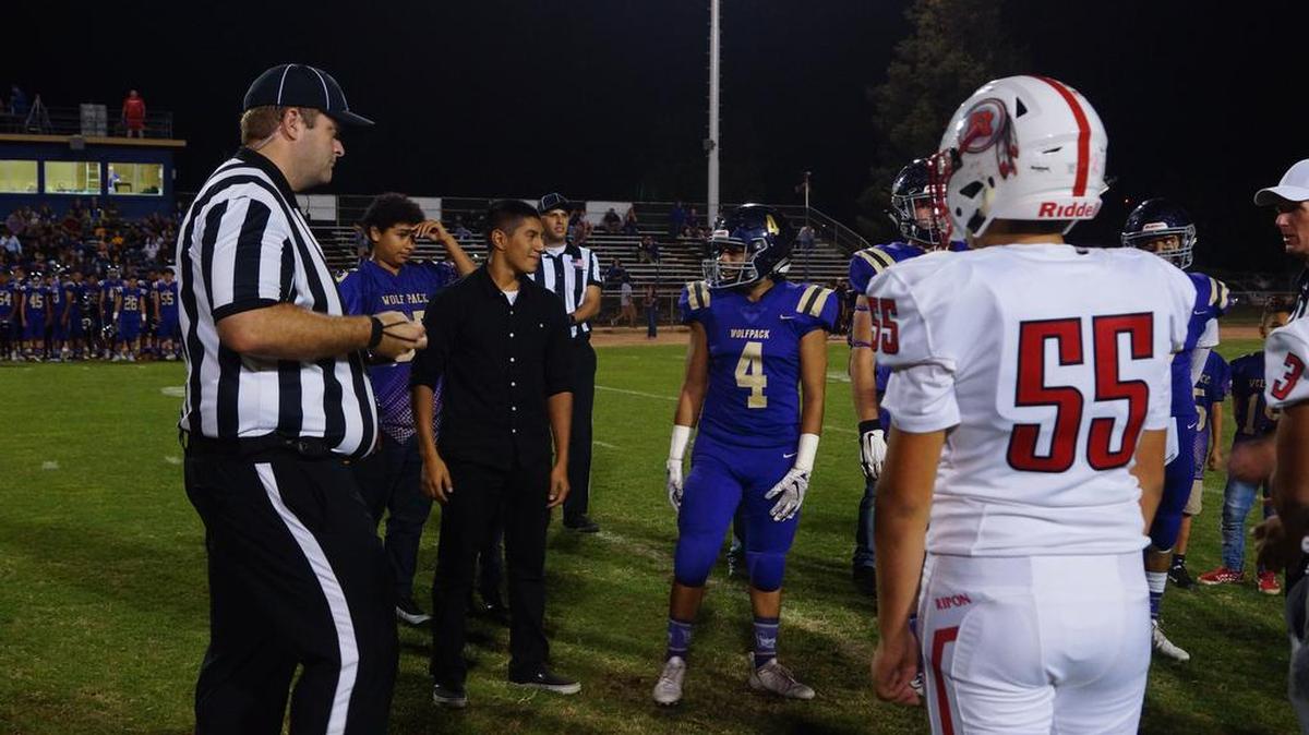 Brothers Mario (left in black) and Daniel Ramos (4) stand together before Livingston High’s football game against Ripon. Mario surprised Daniel by showing up as an honorary captain. Mario is a Marine stationed in Japan and hasn’t seen Daniel in over 2 years.