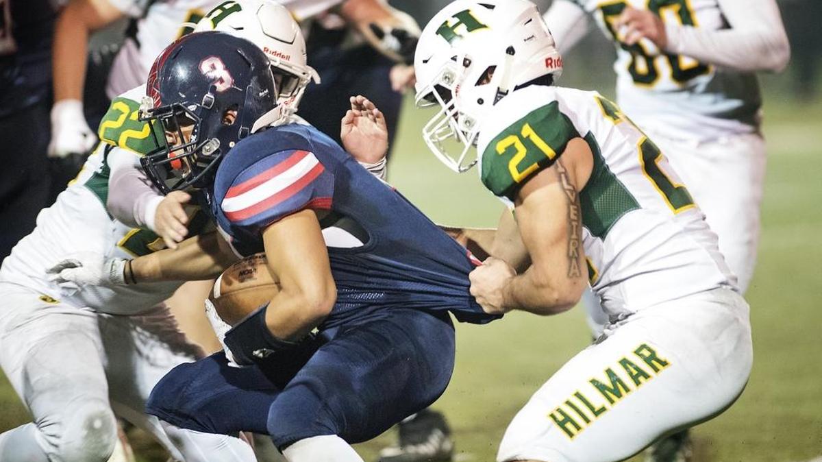 Hilmar's Joao Silveira (21) grabs Modesto Christian's Isaiah Torres for a loss during the Sac-Joaquin Section Division VI final at Lincoln High School in Stockton, Calif., on Saturday, Nov. 25, 2017. Hilmar won the game 42-13.