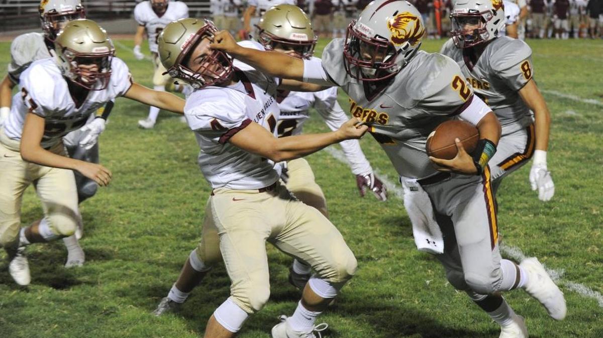 Los Banos High quarterback Anthony Caballero, right, stiff-arms Golden Valley tackler Jakob Rodriguez in game earlier this season. His six touchdown passes last week against Dos Palos may be a school record.