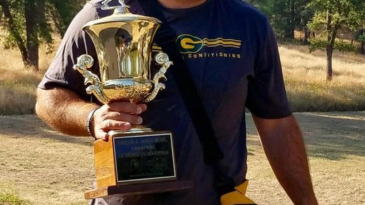 Mariposa High football coach Ryan Oliphant is pictured holding the Green and Gold Trophy, the prize awarded annually to the winner of the Mariposa-Le Grand rivalry game. Oliphant grabbed the trophy before he and his family were evacuated from their home on July 18, 2017 because of the Detwiler fire.