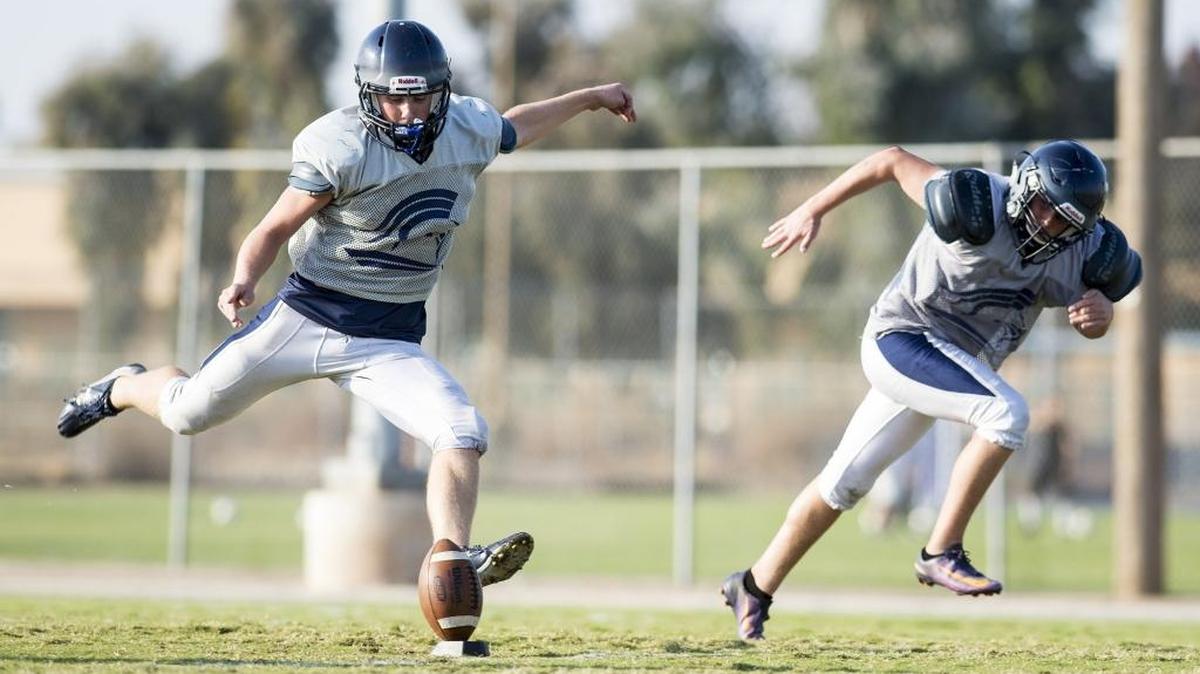 Stone Ridge Christian senior quarterback Bryce Louters, left, kicks the ball during varsity football practice in Atwater, Calif., on Wednesday, Nov. 1, 2017.